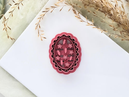 Wavy oval frame cutter with tiny strawberry and flower stamp details for summer themed polymer clay earring making.