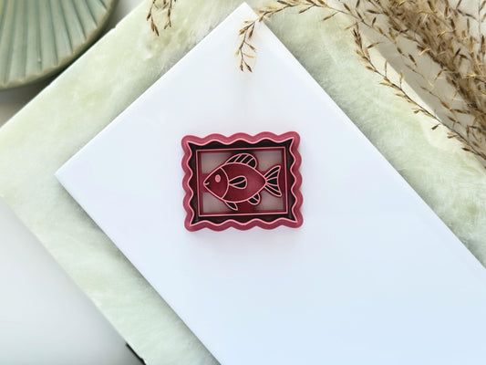 Pink wave edged rectangle frame polymer clay earring cutter with inner fish stamp details.