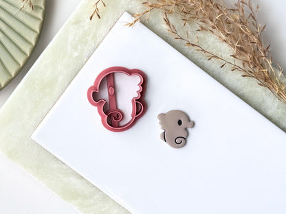 Cartoon style seahorse cutter with eye and curled tail. Next to the cutter is a polymer clay seahorse shaped cut out made from the cutter.