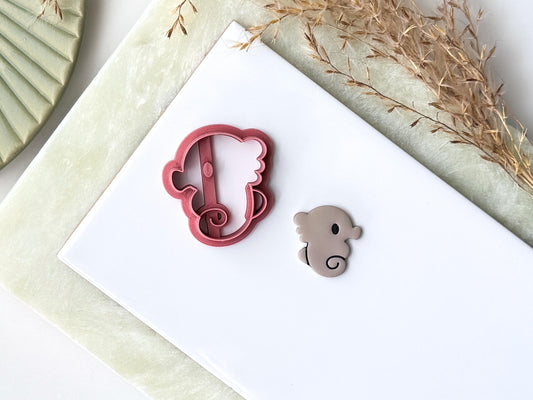 Cartoon style seahorse cutter with eye and curled tail. Next to the cutter is a polymer clay seahorse shaped cut out made from the cutter.