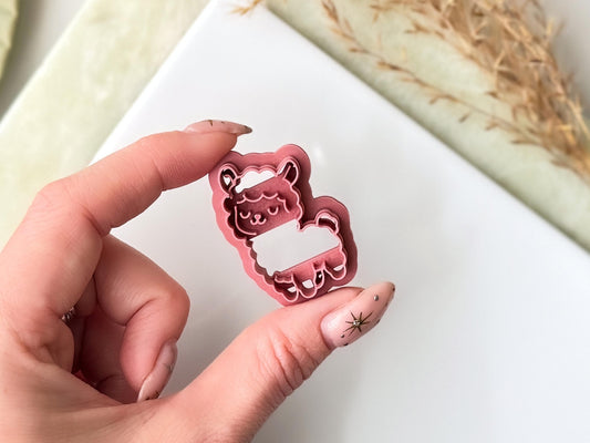 A dusty rose coloured clay cutter shaped like a llama with a closed-eye expression. The cutter features a detailed outline of the animal's head, ears, and body, designed to create a stamped impression in clay or other soft materials.
