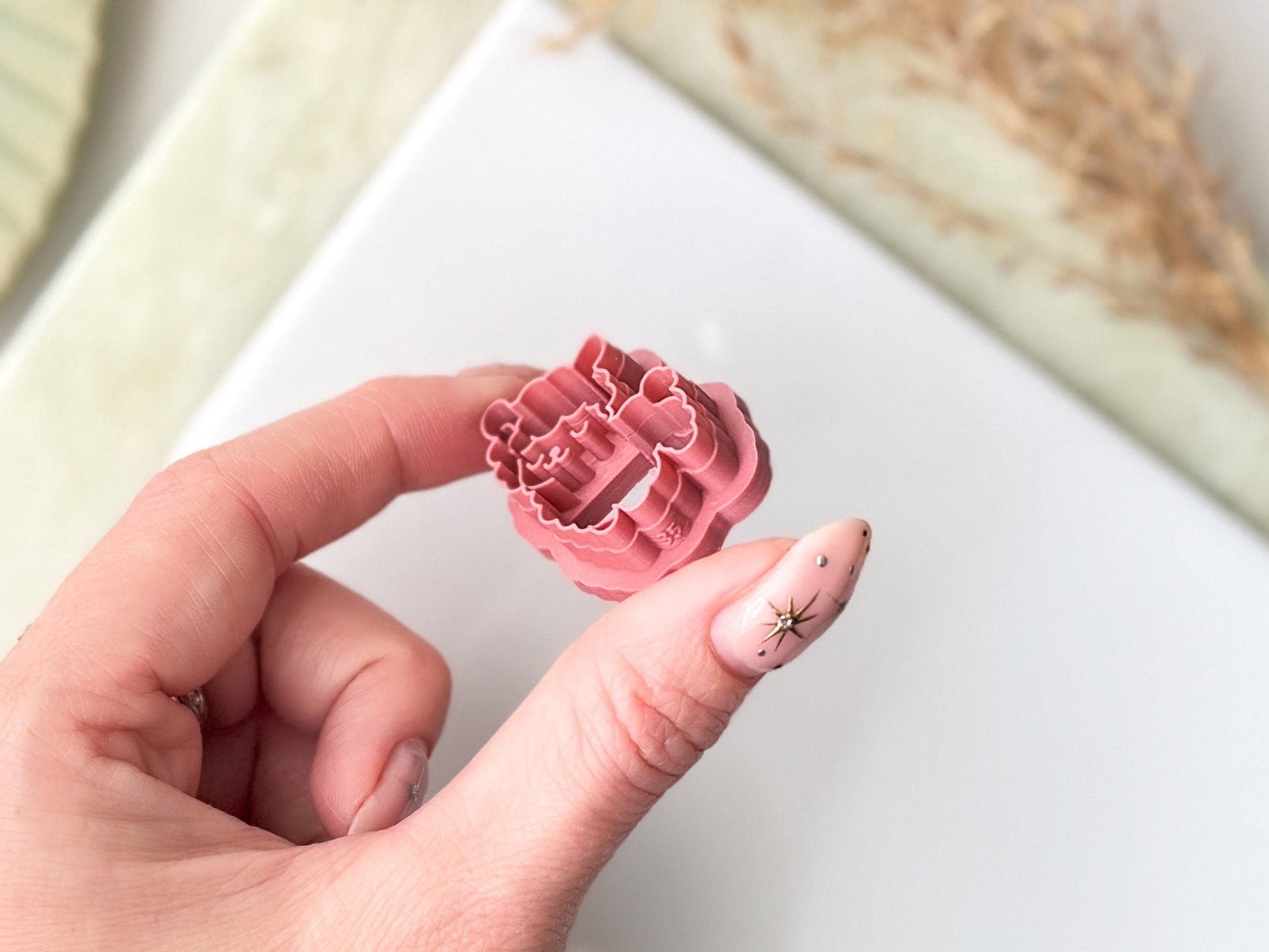 A small, pink, three-dimensional clay cutter featuring a detailed outline of a llama or alpaca character with a rounded head, pointed ears, and a woolly coat. The plastic tool has a raised edge for cutting clay or fondant and a sturdy handle for gripping.