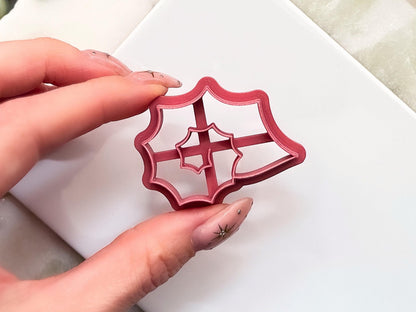 Close up of pink spiky seashell clay cutter featuring a spiral centre. The cutter is being held in a hand.