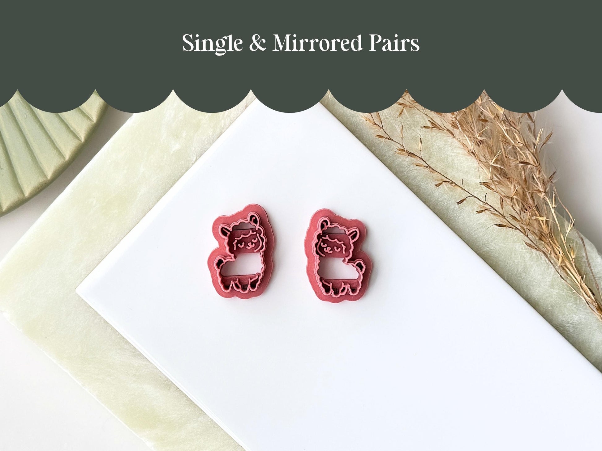 Two dark pink plastic clay cutters shaped like llamas, featuring a mirrored design. Each cutter has a detailed outline of a llama with closed eyes and a smiling expression. The text "Single & Mirrored Pairs" is visible at the top.