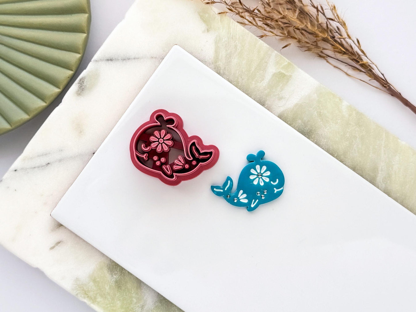 Whale polymer clay cutter with floral embossed design shown alongside matching blue clay cut-out on a white tile. UK-made clay tool for earrings, jewellery, fondant and craft projects.