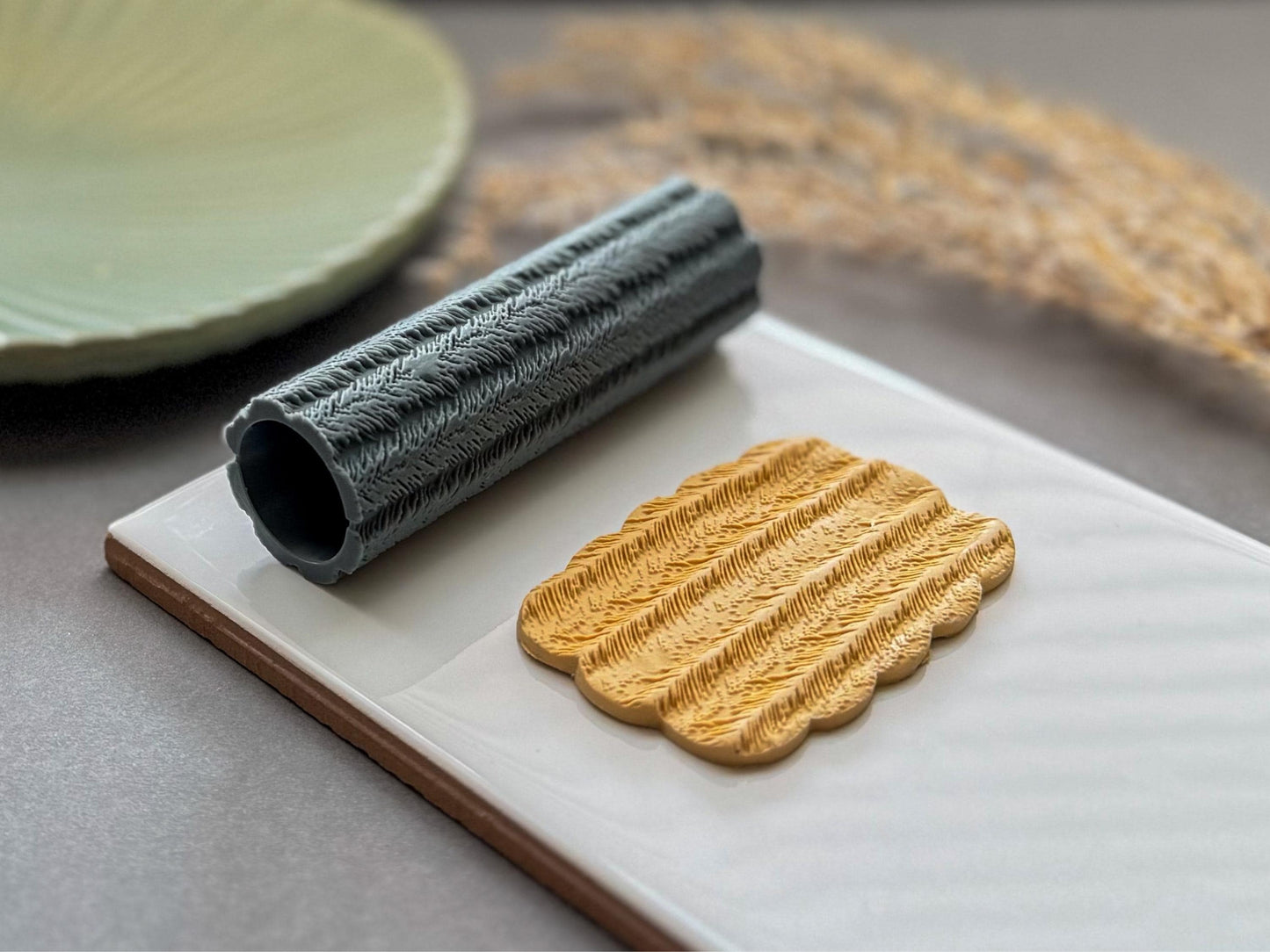 Feather patterned clay roller for creating textured polymer clay earrings and pendants.