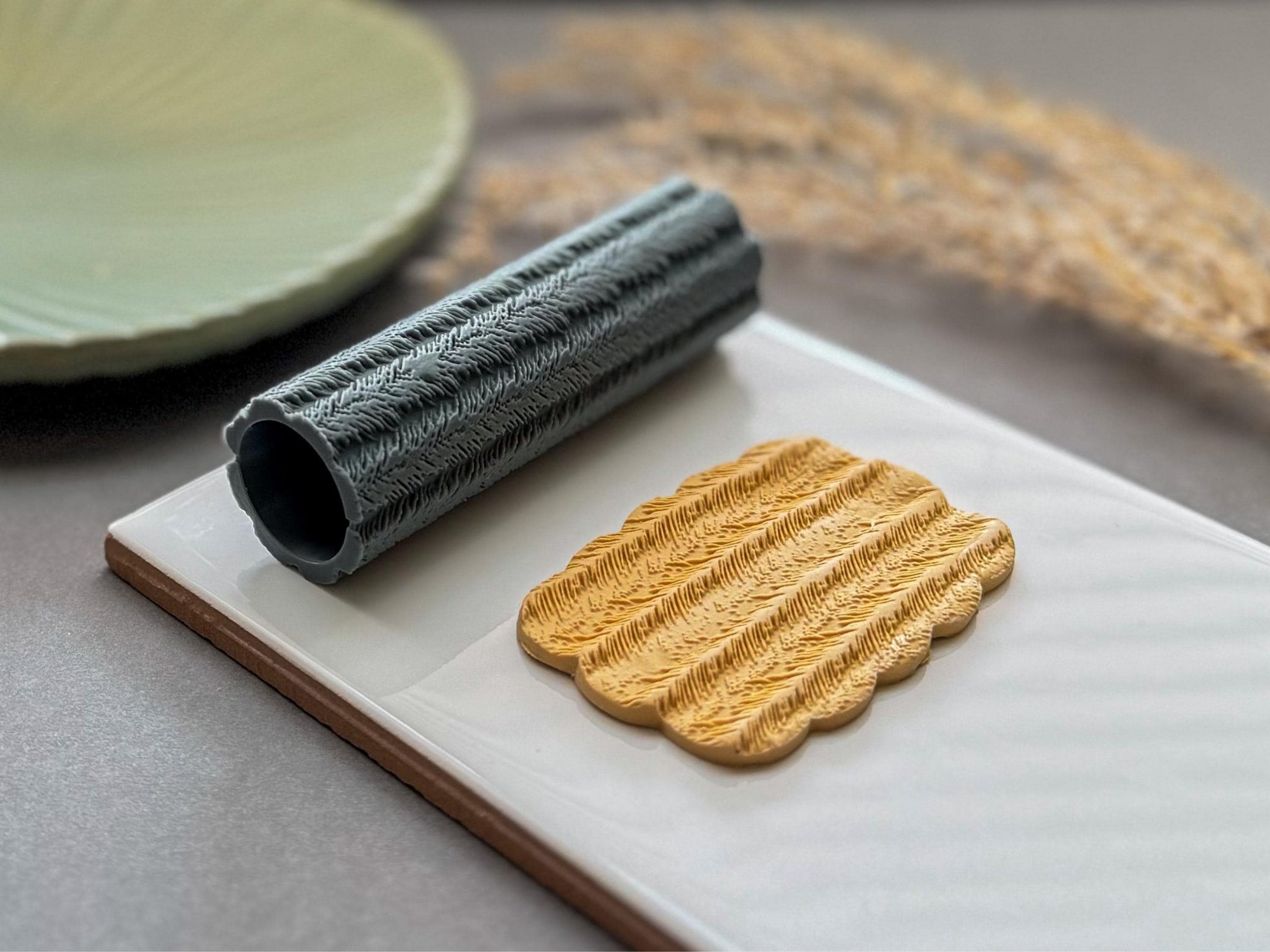 Feather patterned clay roller for creating textured polymer clay earrings and pendants.
