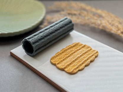Feather patterned clay roller for creating textured polymer clay earrings and pendants.
