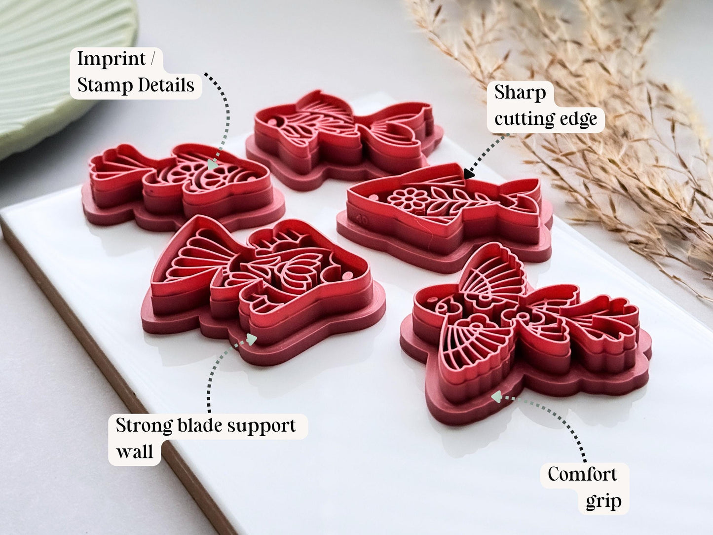 Side view of five folk art fish polymer clay cutters highlighting the sharp cutting edges, detailed imprint stamps, reinforced support walls and comfortable grip handles. Displayed on a white ceramic tile.