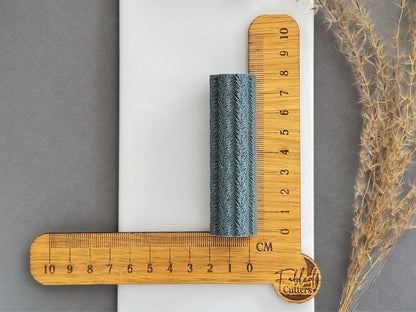 Feather texture roller shown beside centimetre ruler to display size for polymer clay projects.