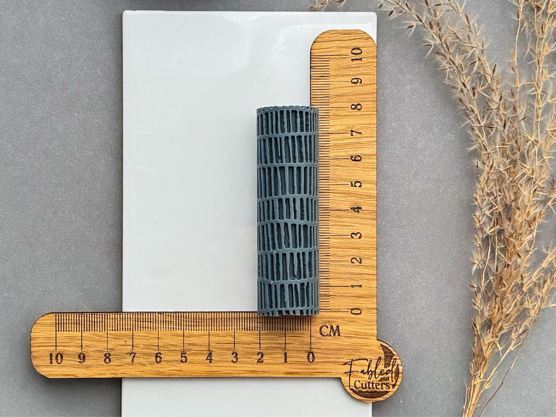 Size reference photo of linear brick texture roller with centimetre ruler for polymer clay.