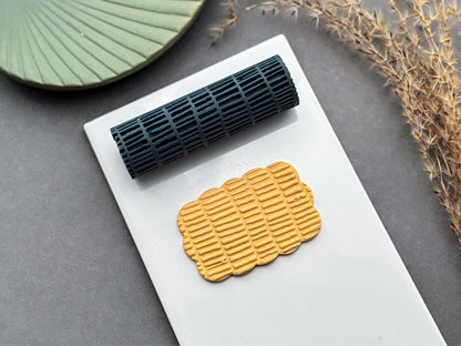 Linear brick texture roller for polymer clay displayed with embossed clay sample on white tile and grey background.