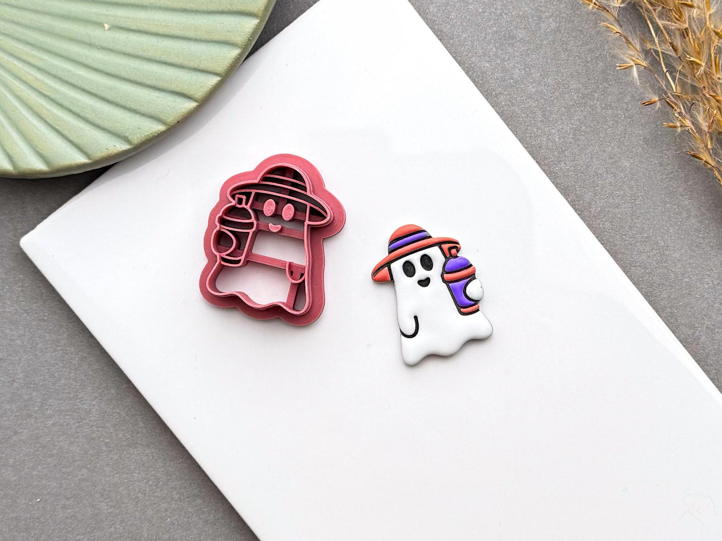 Cute summer ghost polymer clay cutter displayed beside a finished ghost earring with a striped smoothie cup.