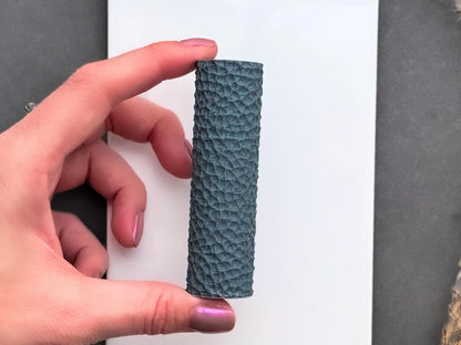 Pebbled leather texture roller held in hand to show size and realistic leather grain detail for polymer clay.