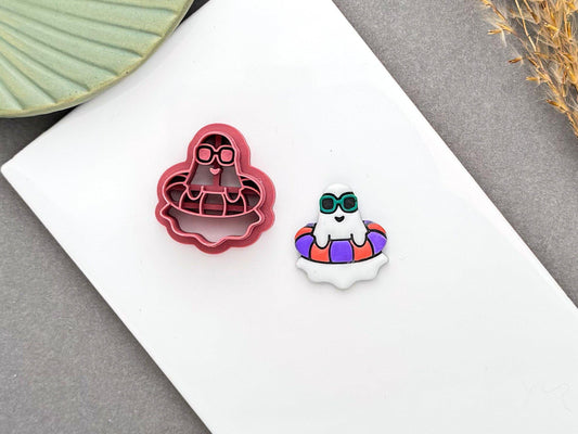 Summer ghost in a pool float polymer clay cutter beside a finished ghost earring with sunglasses and a colourful swim ring.