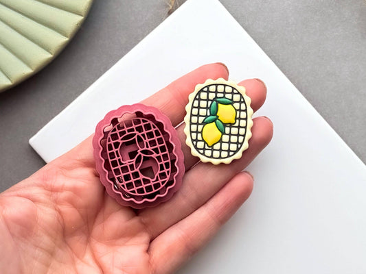 Lemon frame polymer clay cutter and matching finished polymer clay embellishment held in a hand for scale, featuring two lemons inside a decorative lattice frame, ideal for citrus, summer fruit and Mediterranean-inspired clay designs.