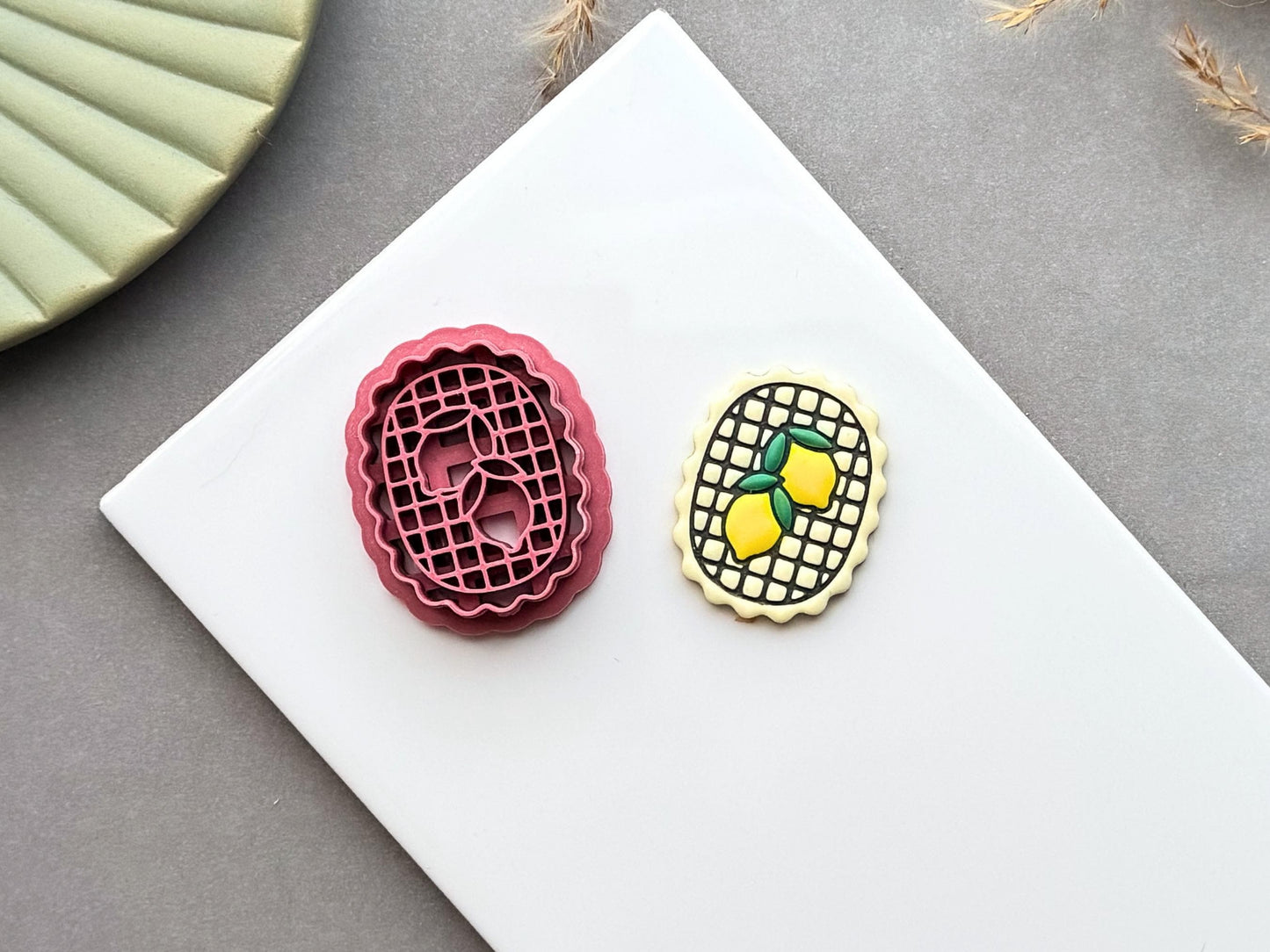 Lemon frame polymer clay cutter displayed beside a matching finished polymer clay embellishment featuring two lemons inside a decorative lattice frame.