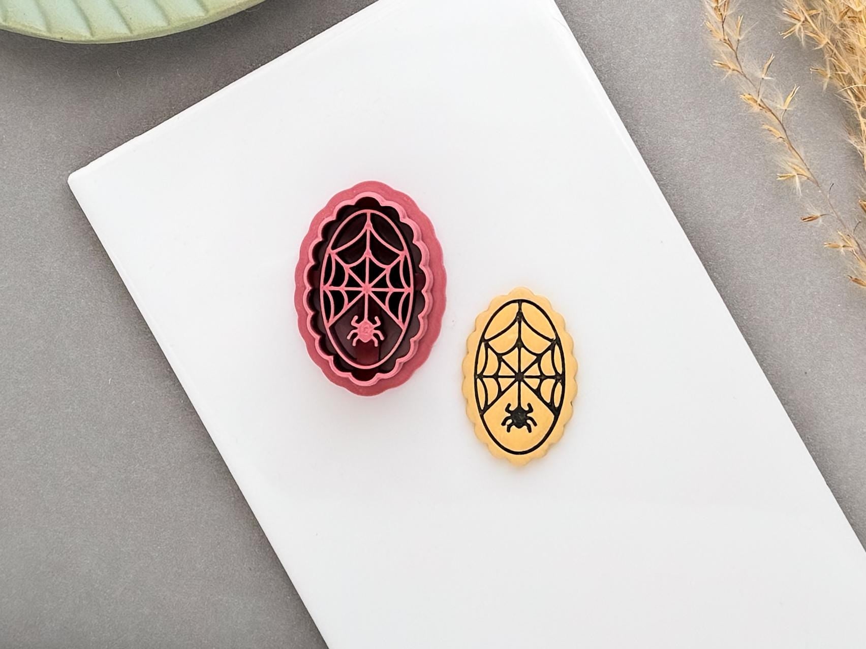 Spider web polymer clay cutter with a small spider displayed beside a matching finished clay embellishment, featuring an intricate web and spider design, perfect for Halloween, gothic and spooky clay projects.
