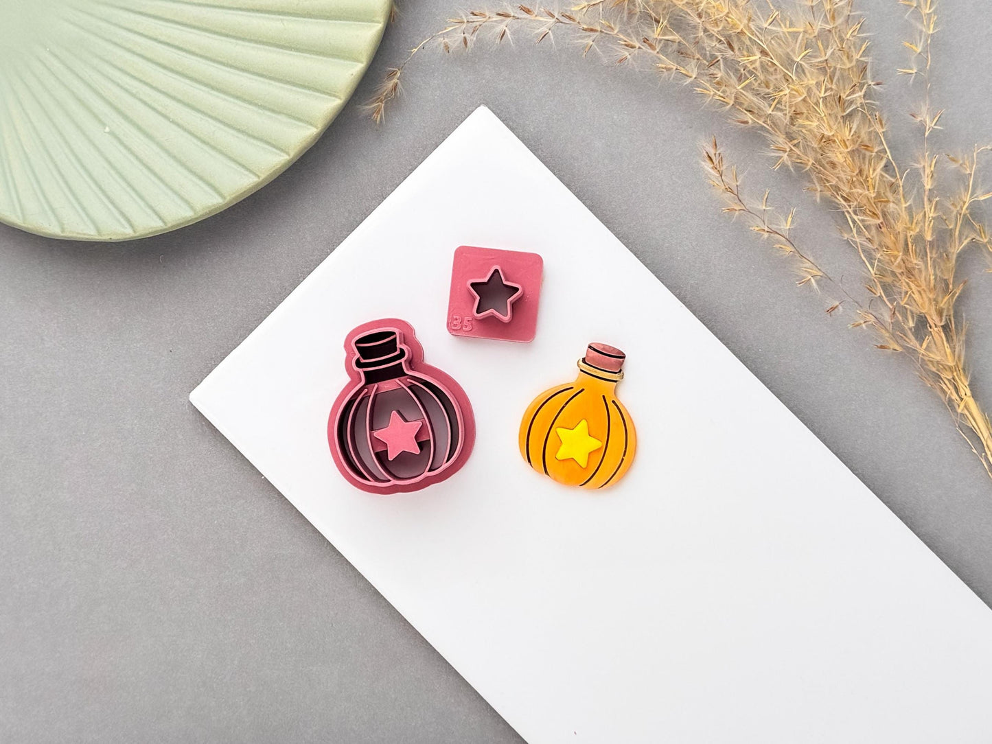 Pumpkin potion bottle polymer clay cutter with star-shaped centre, shown with a matching finished clay piece and small star cutter on a white surface.