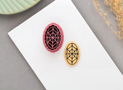 Spider web polymer clay cutter displayed beside a matching finished clay embellishment, featuring an intricate spider web design, perfect for Halloween, gothic and spooky clay projects.