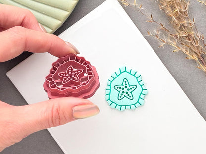 Starfish polymer clay cutter held in hand, showing the detailed stamp design and layered cutting edge beside a finished turquoise starfish clay piece