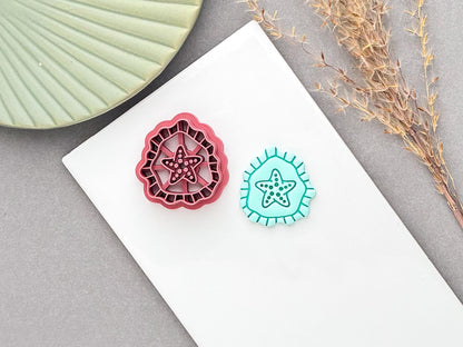 Starfish polymer clay cutter with detailed stamp design, shown beside a finished turquoise clay starfish embellishment on a white surface.