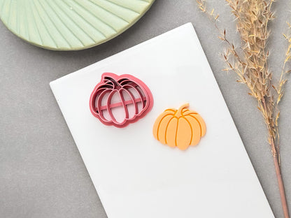 Pumpkin polymer clay cutter with a detailed segmented pumpkin design and curved stem, shown alongside a finished orange pumpkin clay piece.