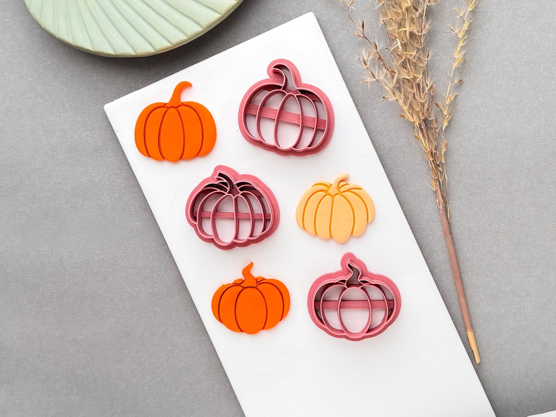 Pumpkin polymer clay cutters in multiple sizes, shown alongside finished orange pumpkin clay pieces on a white surface, with a seasonal autumn theme.