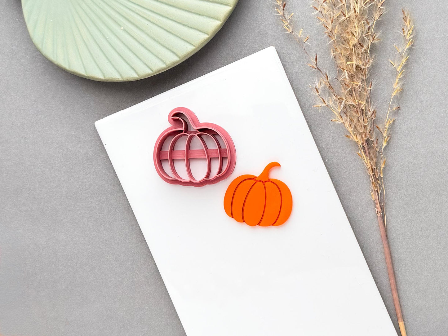 Pumpkin polymer clay cutter shown alongside a finished orange pumpkin clay piece, clearly showing the cutter design and resulting cut-out shape.