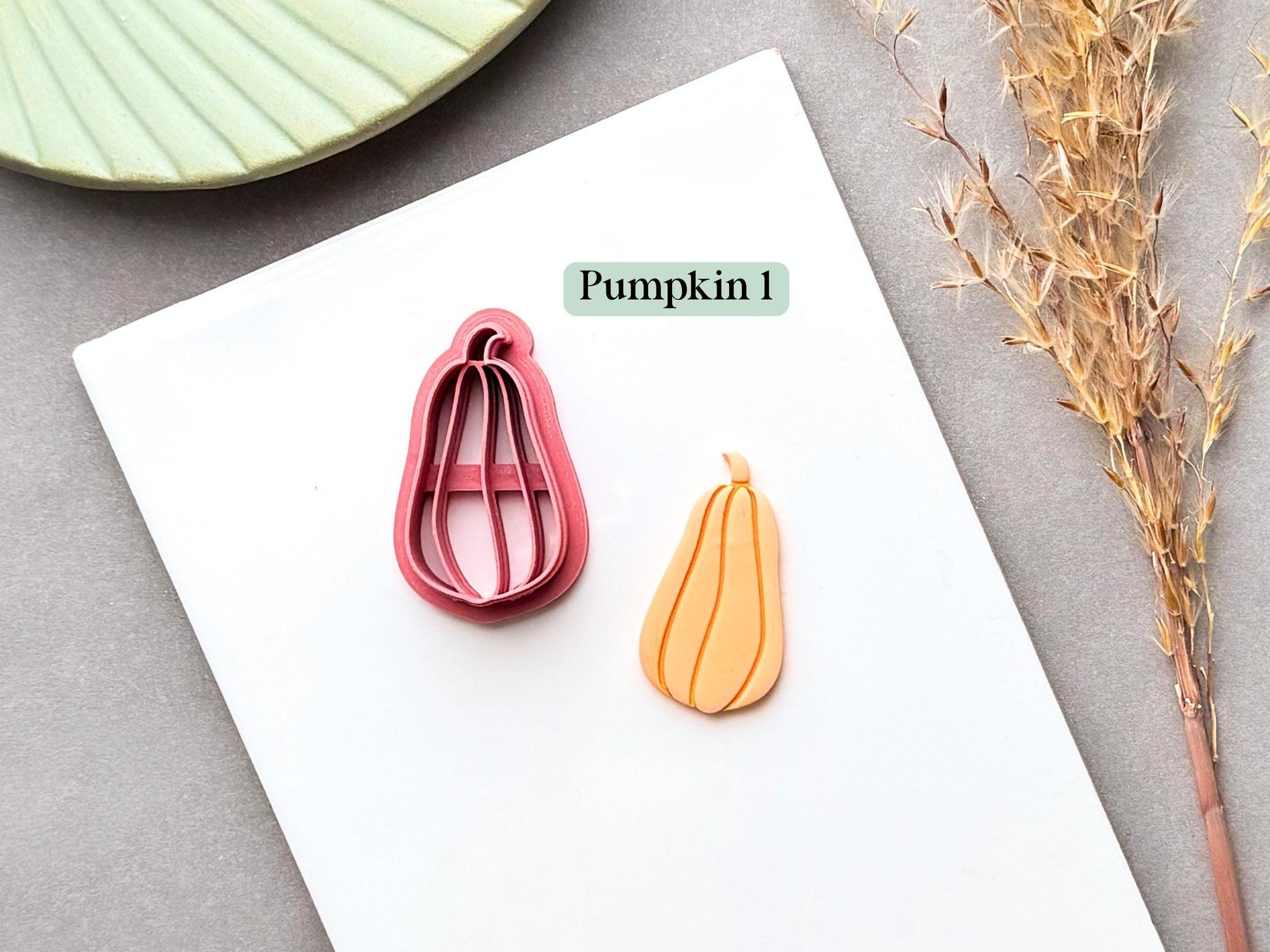 Pumpkin polymer clay cutter featuring an elongated, teardrop-shaped squash or pumpkin with a narrow rounded top and curled stem, shown alongside a finished clay pumpkin piece.