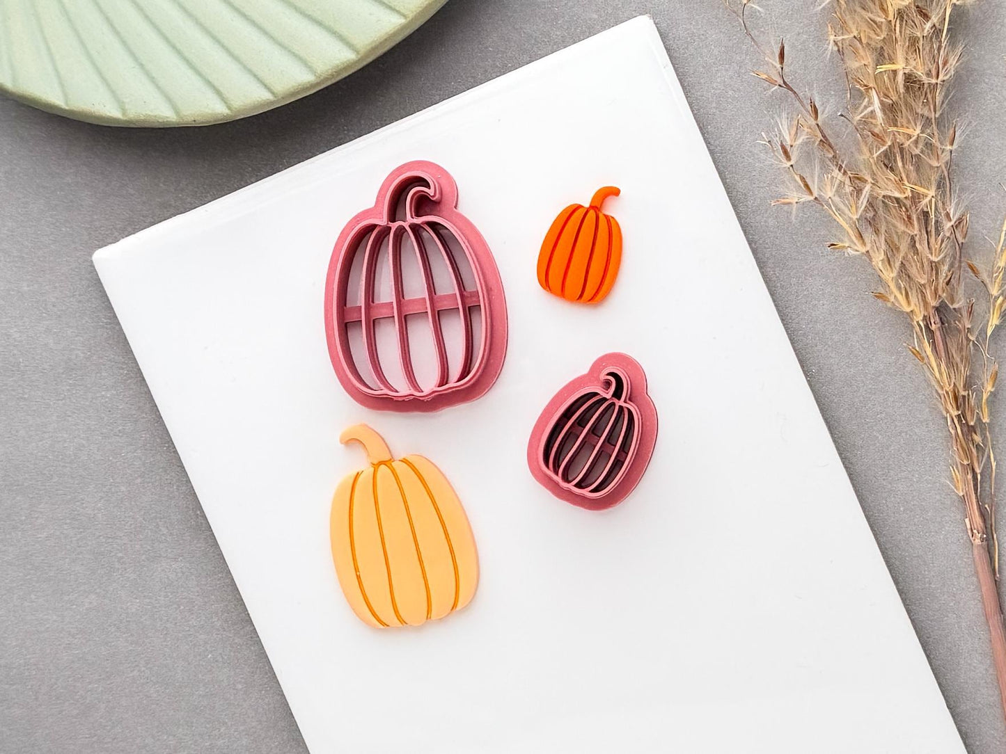 Pumpkin polymer clay cutter with a rounded pumpkin shape and curled stem, shown alongside a finished orange pumpkin clay piece.