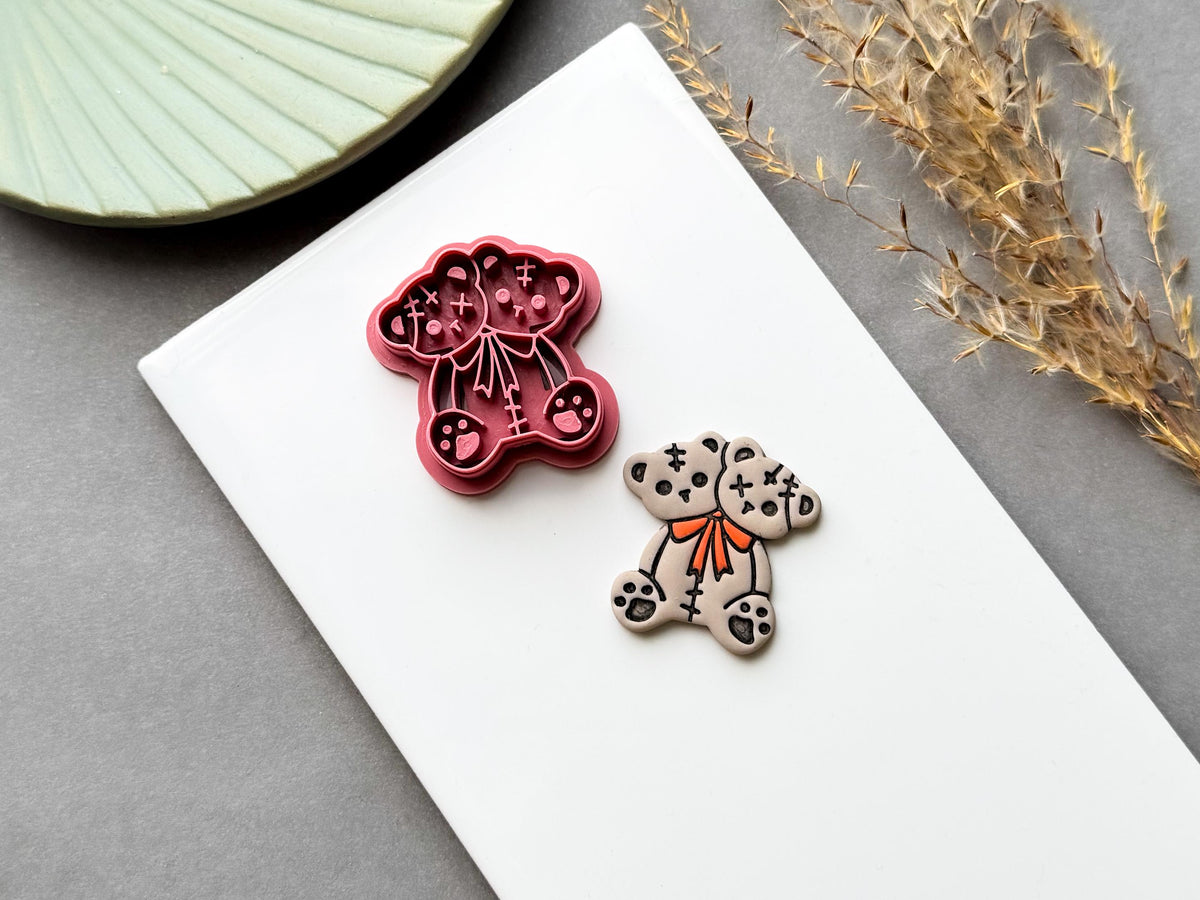 Two-headed Halloween teddy bear clay cutter featuring stitched patchwork details, cross-shaped stitches, paw details and a bow tie, shown beside a finished cream polymer clay bear. Spooky, gothic and alternative Halloween-inspired design.
