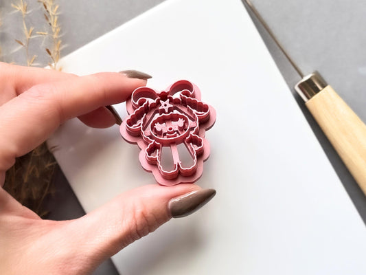Baphomet clay cutter held in a hand, showing the detailed horned figure, bat-like wings, pentagram symbol, facial details and raised cutting edge.