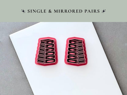 Two stack of books clay cutters displayed as a mirrored pair, each featuring detailed book spines, page edges and raised spine accents. Pink 3D-printed cutters shown on a white surface beneath a “Single & Mirrored Pairs” heading.