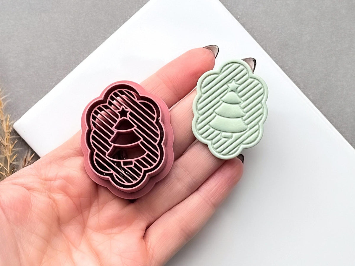 Pink polymer clay cutter shaped like a scalloped Christmas tree with diagonal striped detail and a small star at the top, shown beside a pale green finished clay tree held in a hand.
