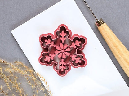 Large snowflake polymer clay ornament cutter featuring a central flower and six decorative branches with leaf-like details, displayed on a white tile.