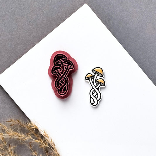 Triple mushroom polymer clay cutter displayed beside a matching finished clay cut-out, featuring three overlapping mushrooms with detailed stems and caps.