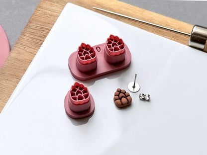 Pine cone polymer clay stamp cutter set displayed in two sizes, featuring detailed scale patterns, with joined double cutters and a separate single cutter alongside a matching finished clay pine cone embellishment and metal earring findings.