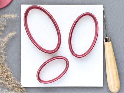 Three large oval polymer clay cutters displayed in different sizes and orientations on a white tile, featuring elongated oval shapes, smooth outlines and raised cutting walls.
