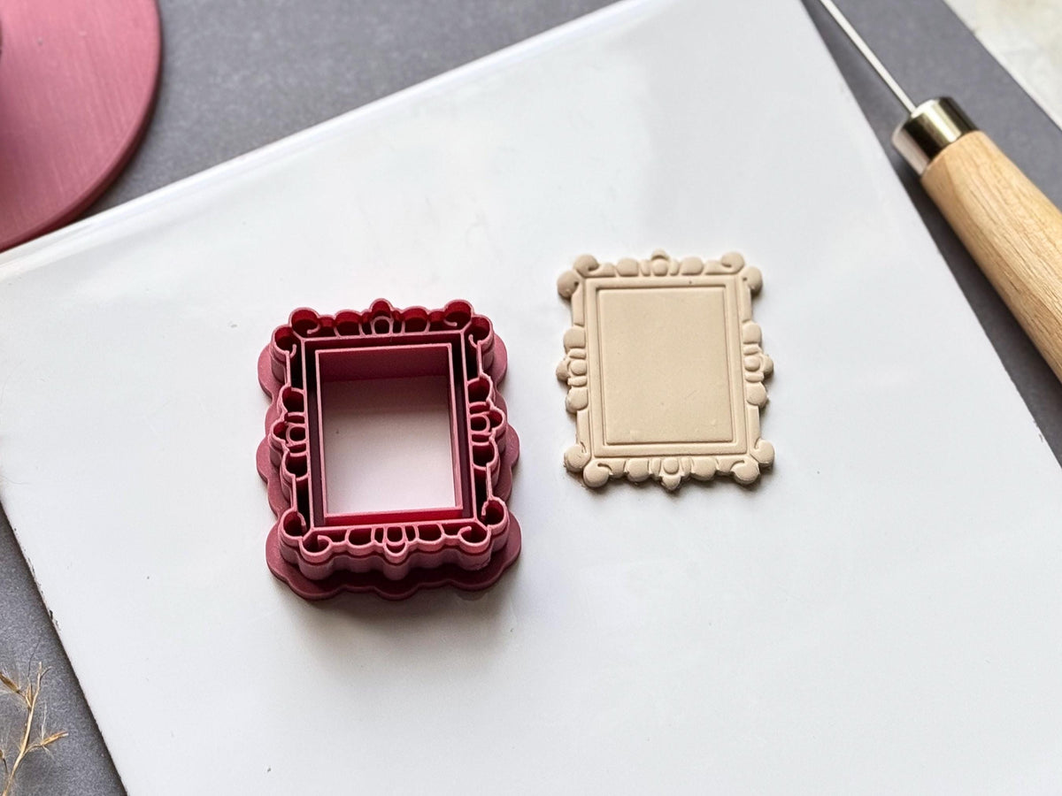 Vintage-style rectangular frame polymer clay cutter displayed beside a matching finished clay frame, featuring an ornate scalloped border with decorative boroque style loop and bead details.