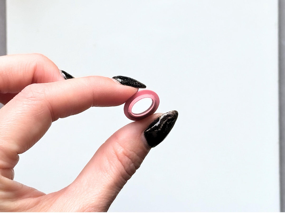 1cm oval polymer clay cutter in pink being held between fingers for scale