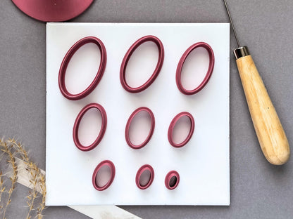 Oval polymer clay cutters displayed in nine sizes on a white tile, ranging from large elongated ovals to small narrow ovals.