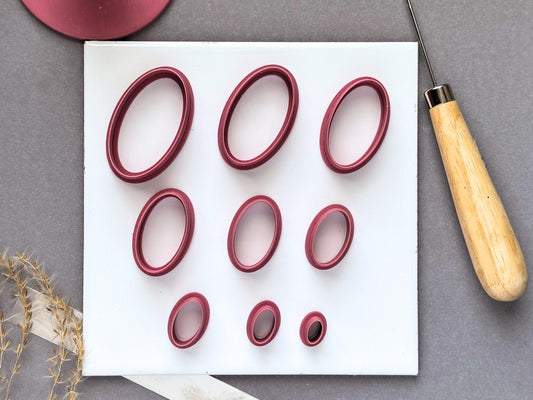Oval polymer clay cutters displayed in nine sizes on a white tile, ranging from large elongated ovals to small narrow ovals.