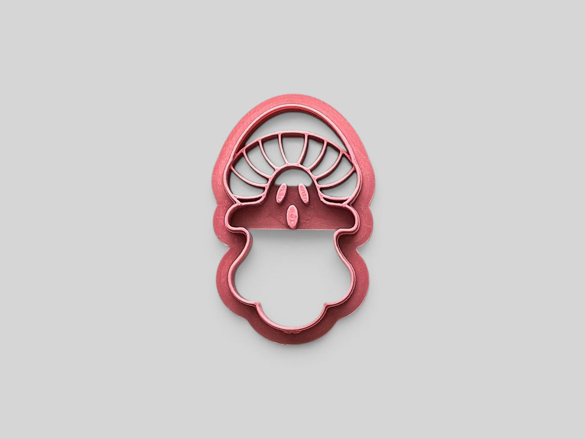 A mushroom-shaped clay cutter in a pink color, shown on a solid light gray background.