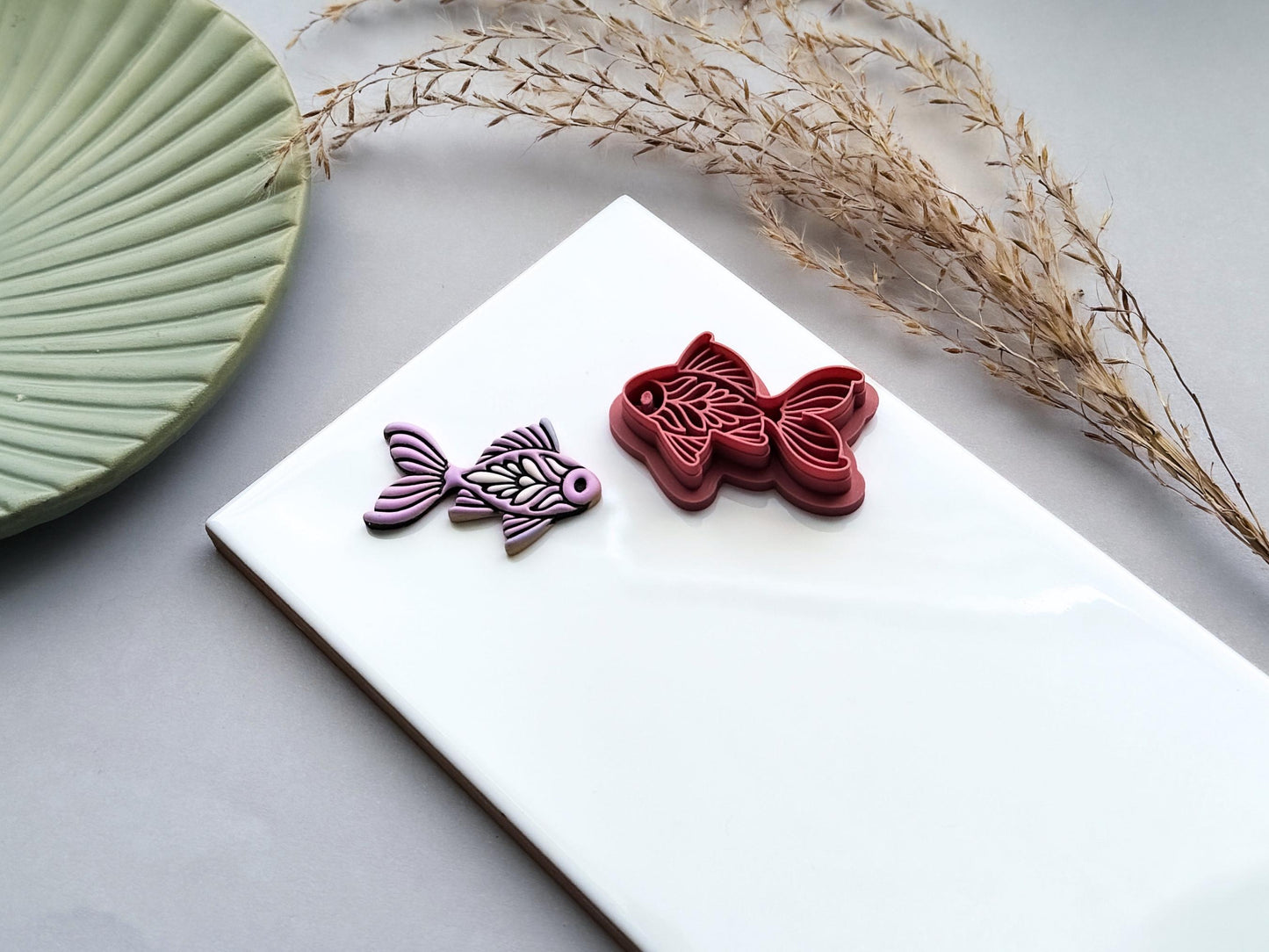 Ornamental fish polymer clay cutter featuring folk art details shown beside a lavender polymer clay cut-out.