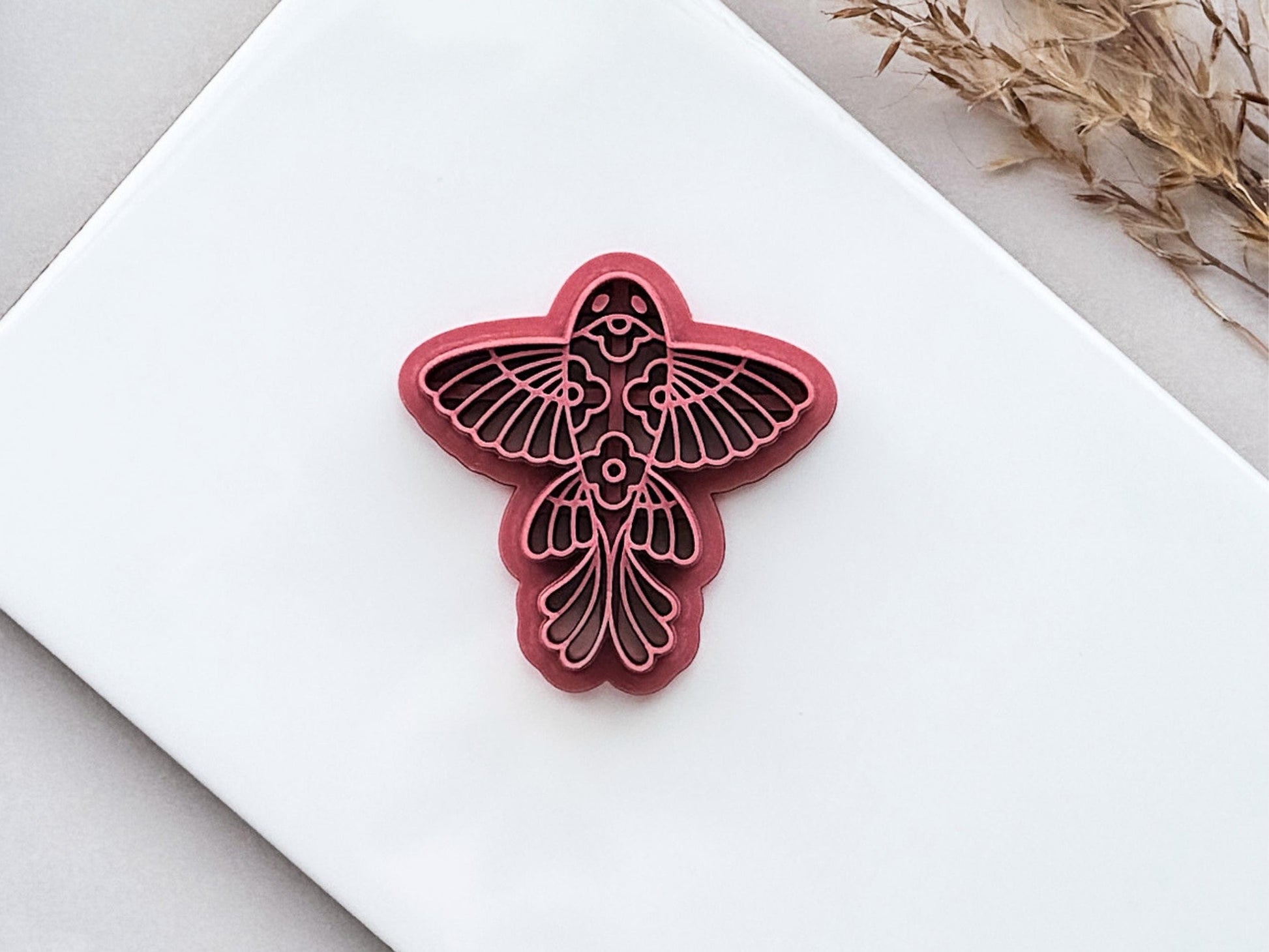 Folk art floral fish polymer clay cutter with embossed floral details on white ceramic tile background
