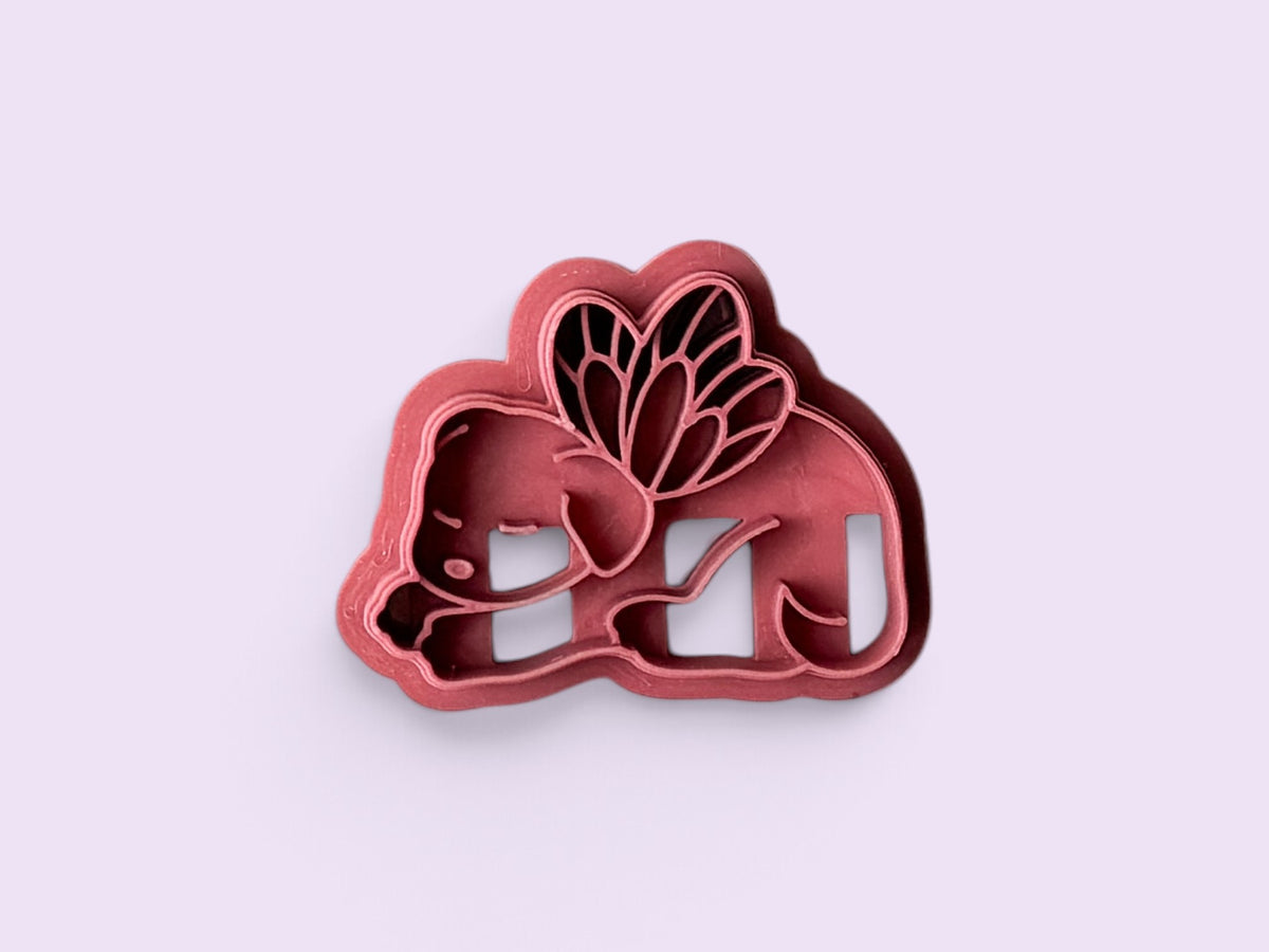 A 3D-printed fairy dog clay cutter in a dusty rose pink color, shown on a solid light lavender background.