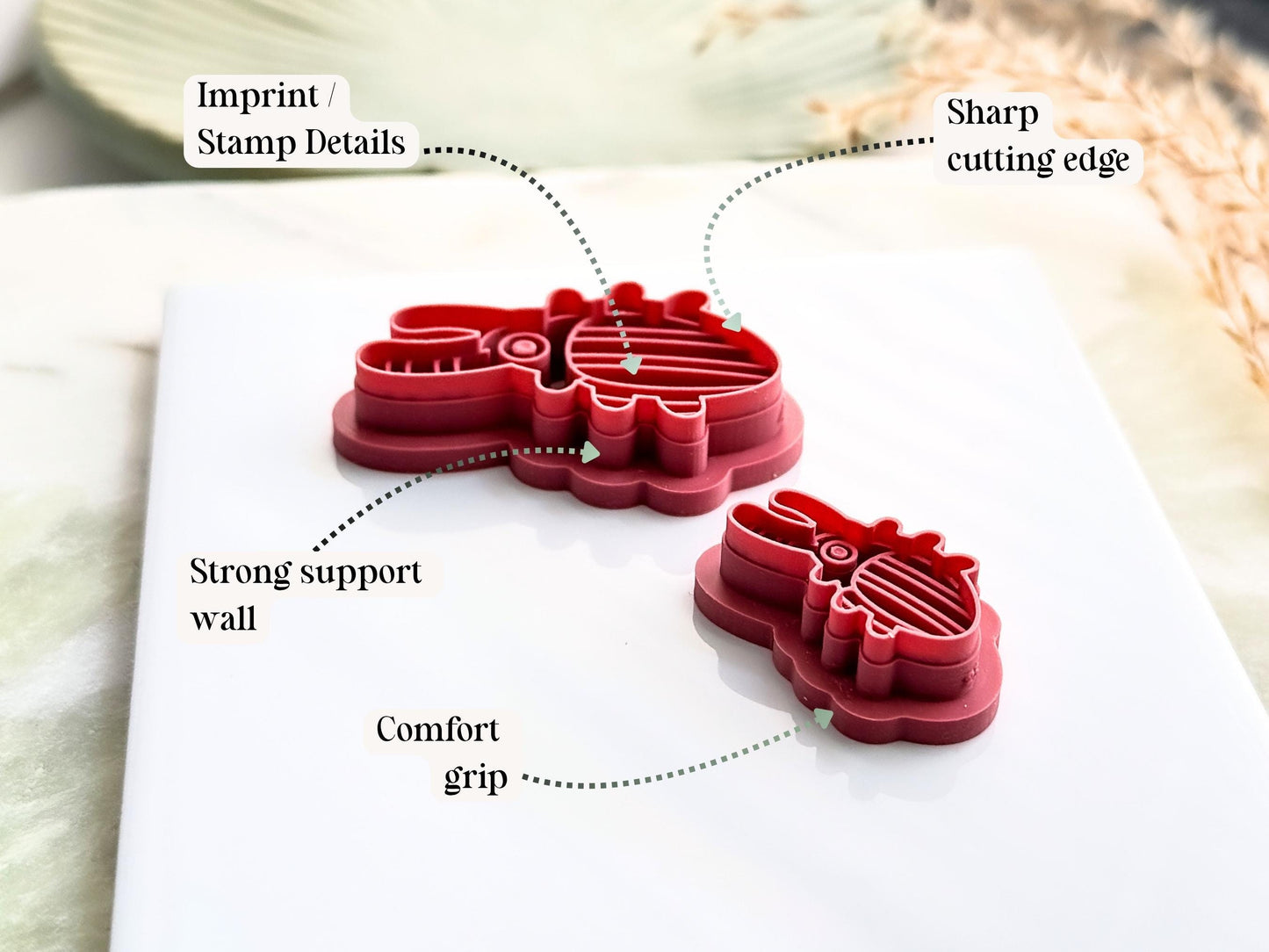 Two stag beetle clay cutters with key feature labels depicting the sharp cutting edge, comfortable grip, strong support wall and imprint or stamp details 