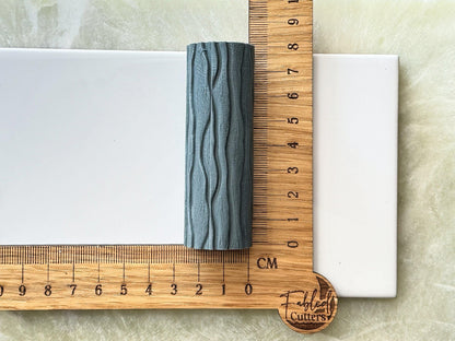 Grey wavy patterned resin texture roller against a ruler to display size 